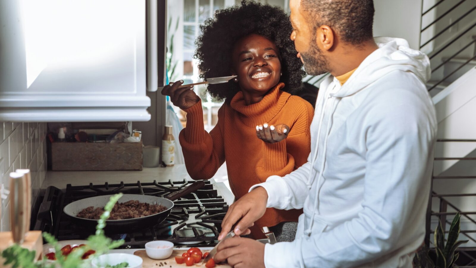 A couple laughing while they cook dinner together