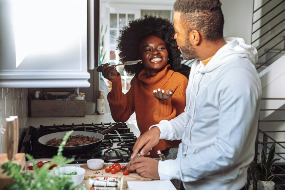 A couple laughing while they cook dinner together