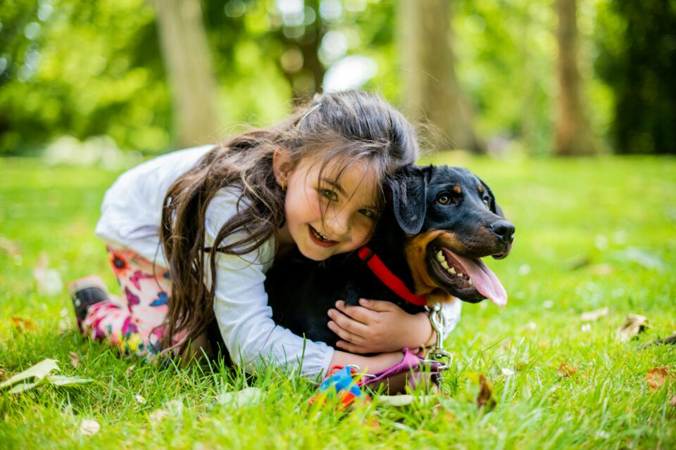 A girl lying in the grass, hugging her dog